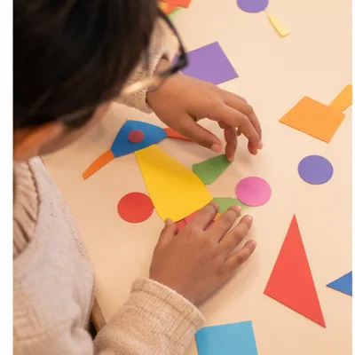 Child arranging colorful shapes creatively